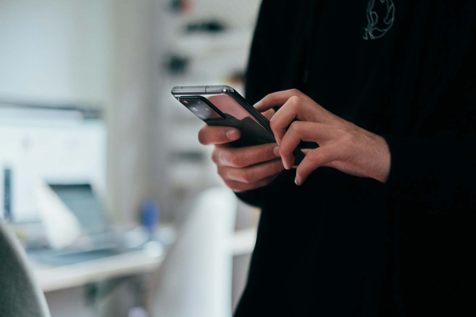 Personne tenant un smartphone noir pour comparer des offres de forfait mobile