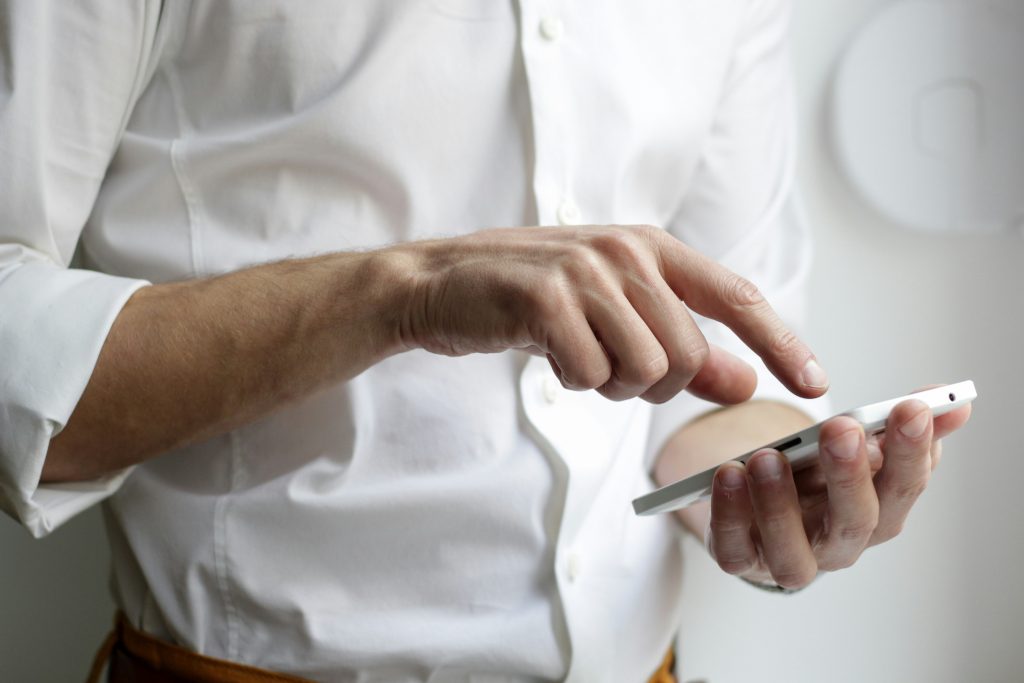 Homme au téléphone inquiet face à un smartphone affichant un appel suspect imitant sa banque