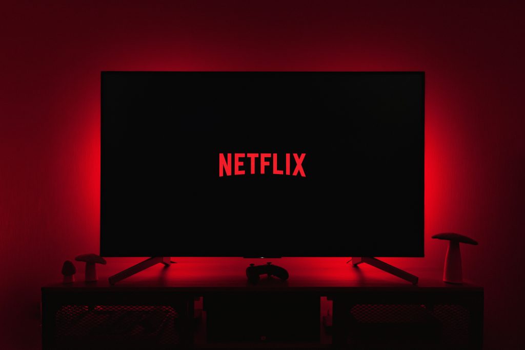 Télévision allumée affichant le logo Netflix dans un salon plongé dans le noir