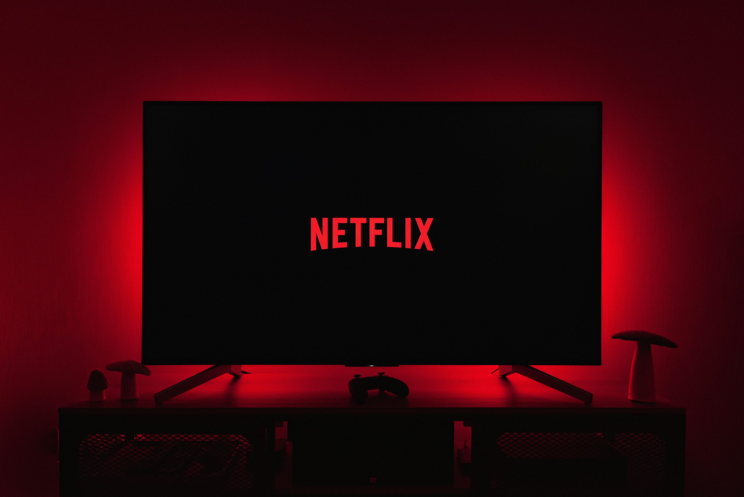 Télévision allumée affichant le logo Netflix dans un salon plongé dans le noir