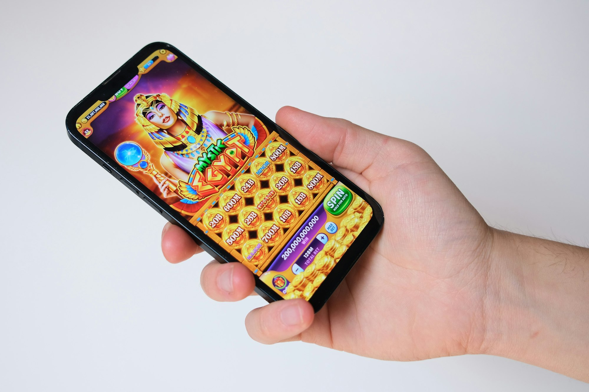 Main tenant un smartphone affichant un jeu de casino en ligne à thème égyptien