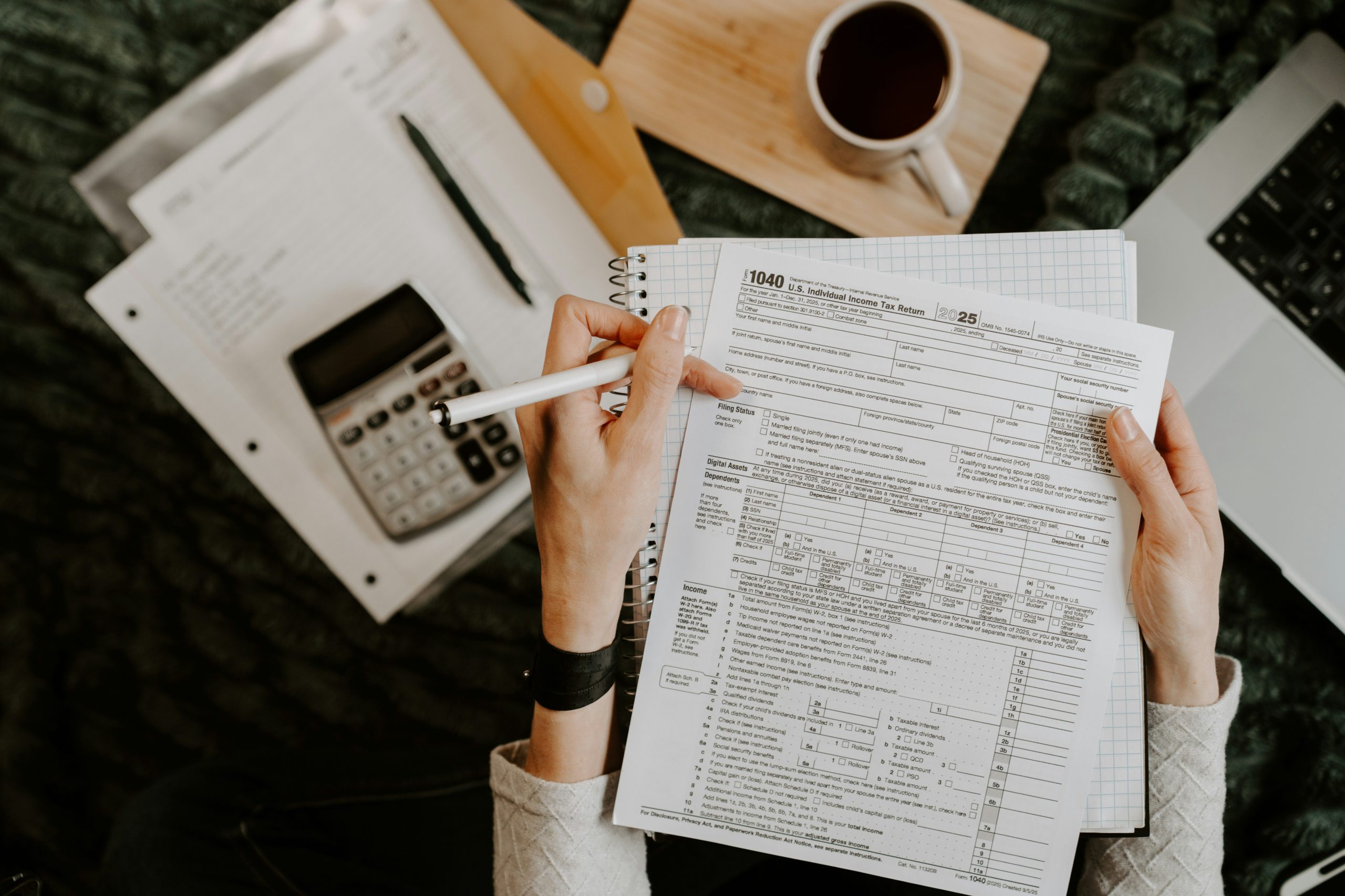 Personne comparant ses factures d'énergie avec une calculatrice et un ordinateur portable