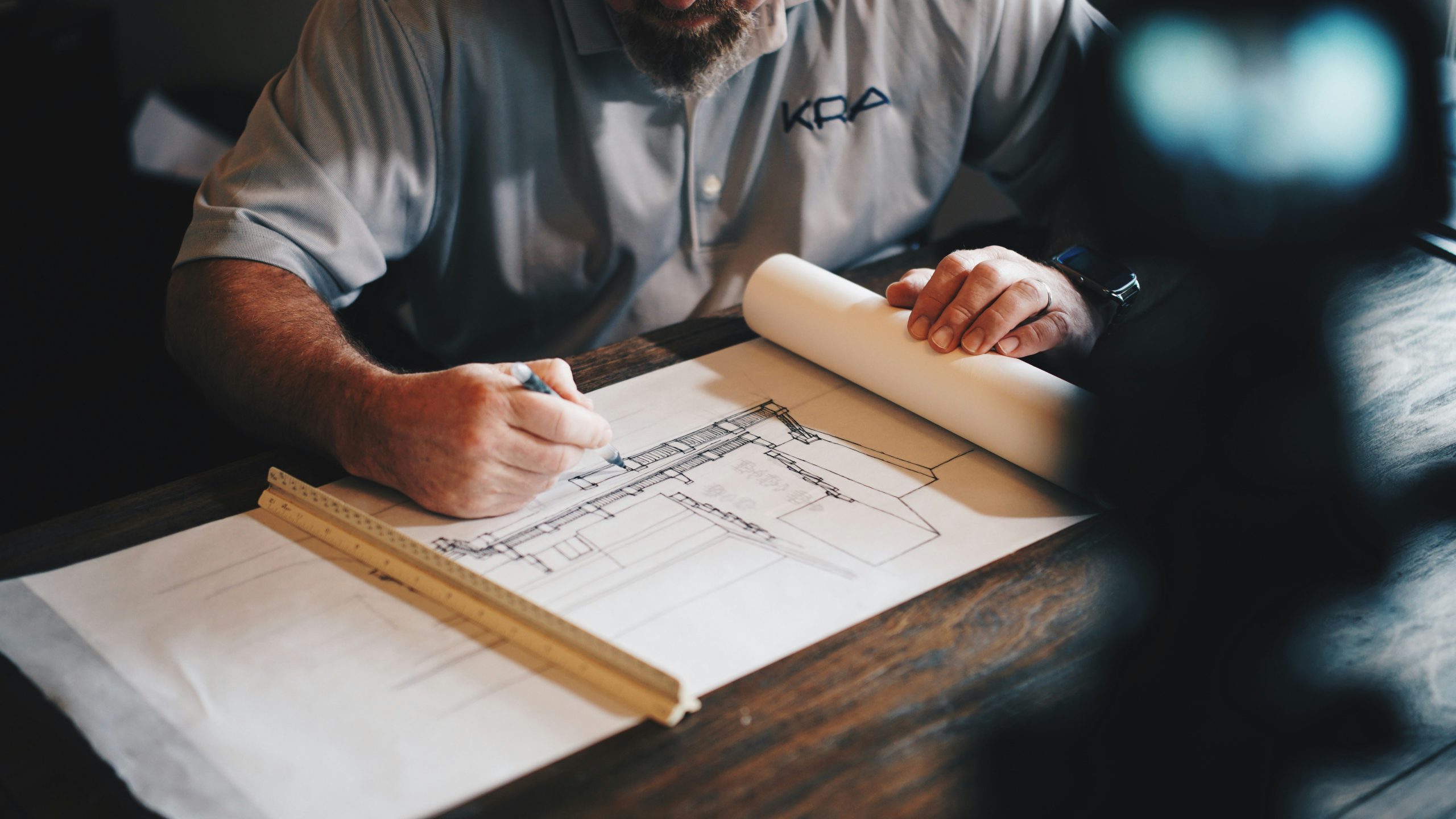 Architecte dessinant un plan de rénovation énergétique avec crayon et règle