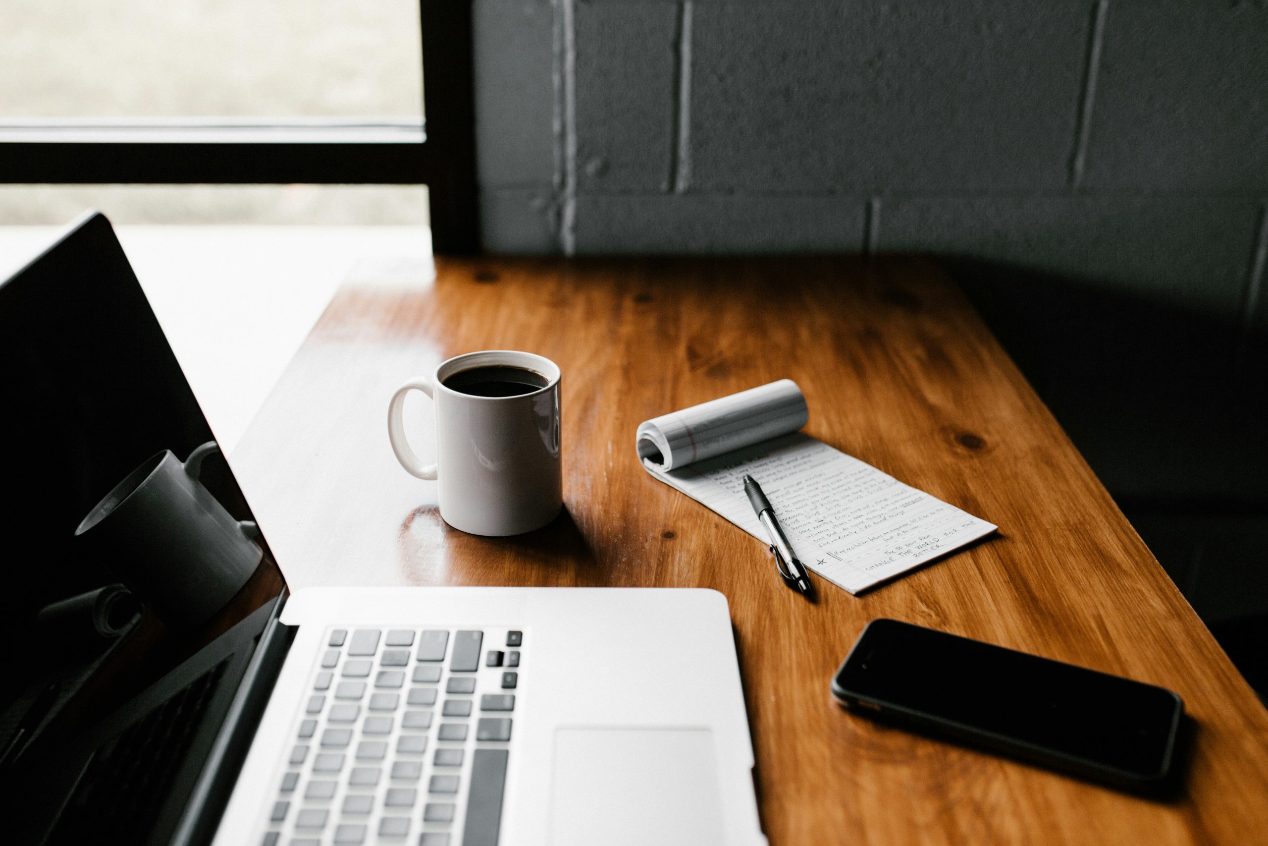 Ordinateur portable et smartphone sur un bureau, outils utilisés pour une activité freelance liée à l'IA