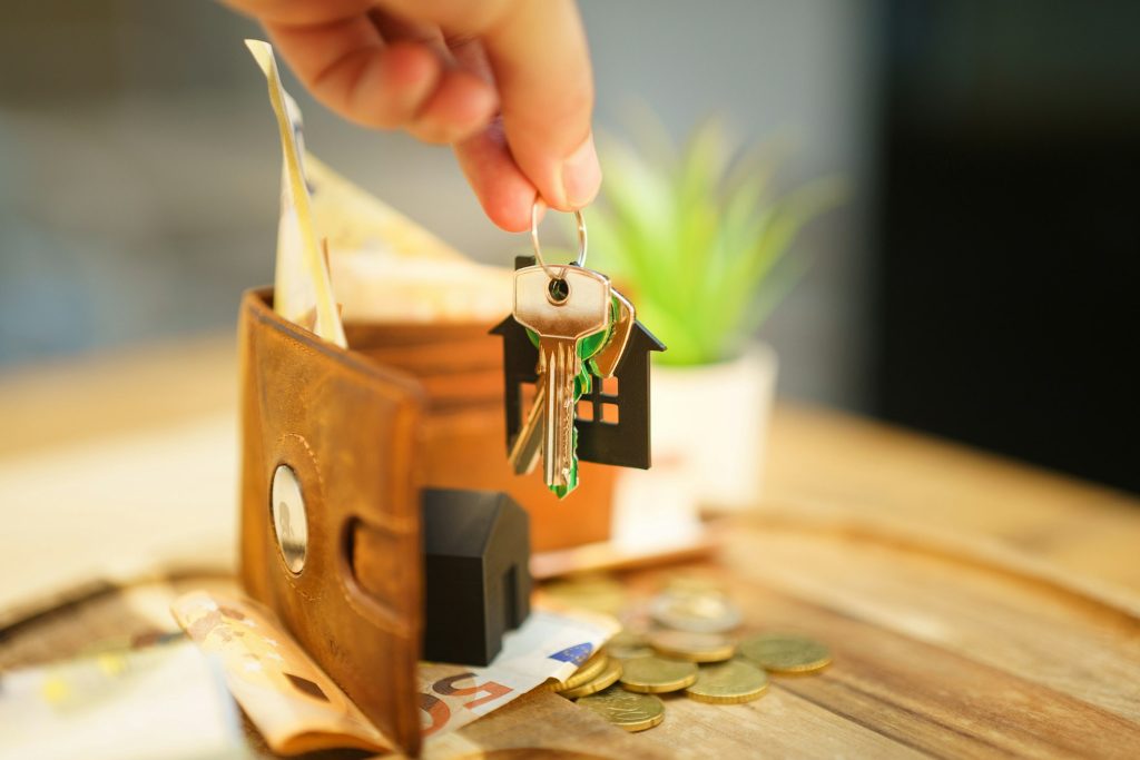 Main tenant des clés de maison avec un porte-clés en forme de maison, symbole de l'assurance habitation