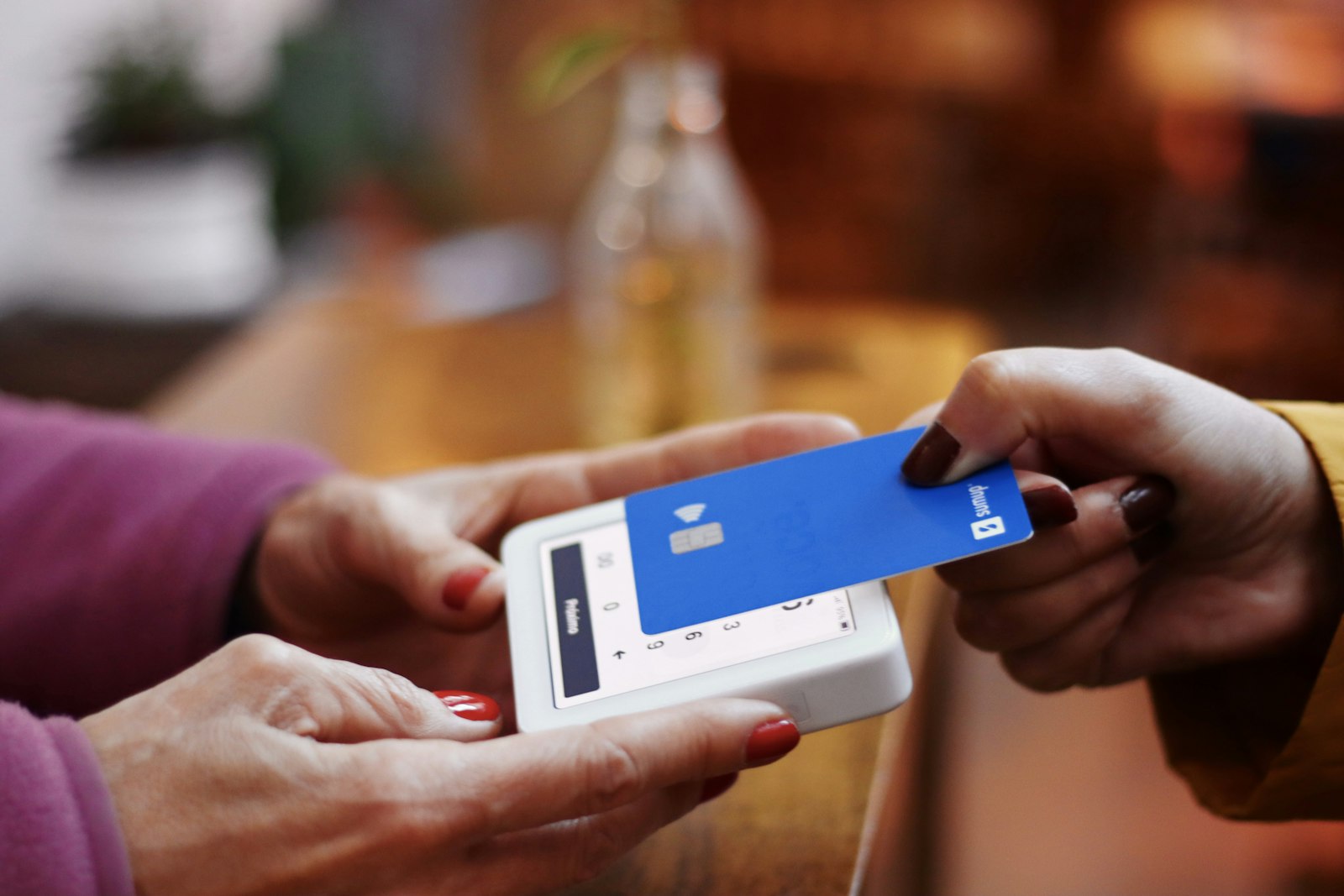 Personne tenant une carte bancaire et un smartphone, illustration du risque de fraude bancaire après un smishing