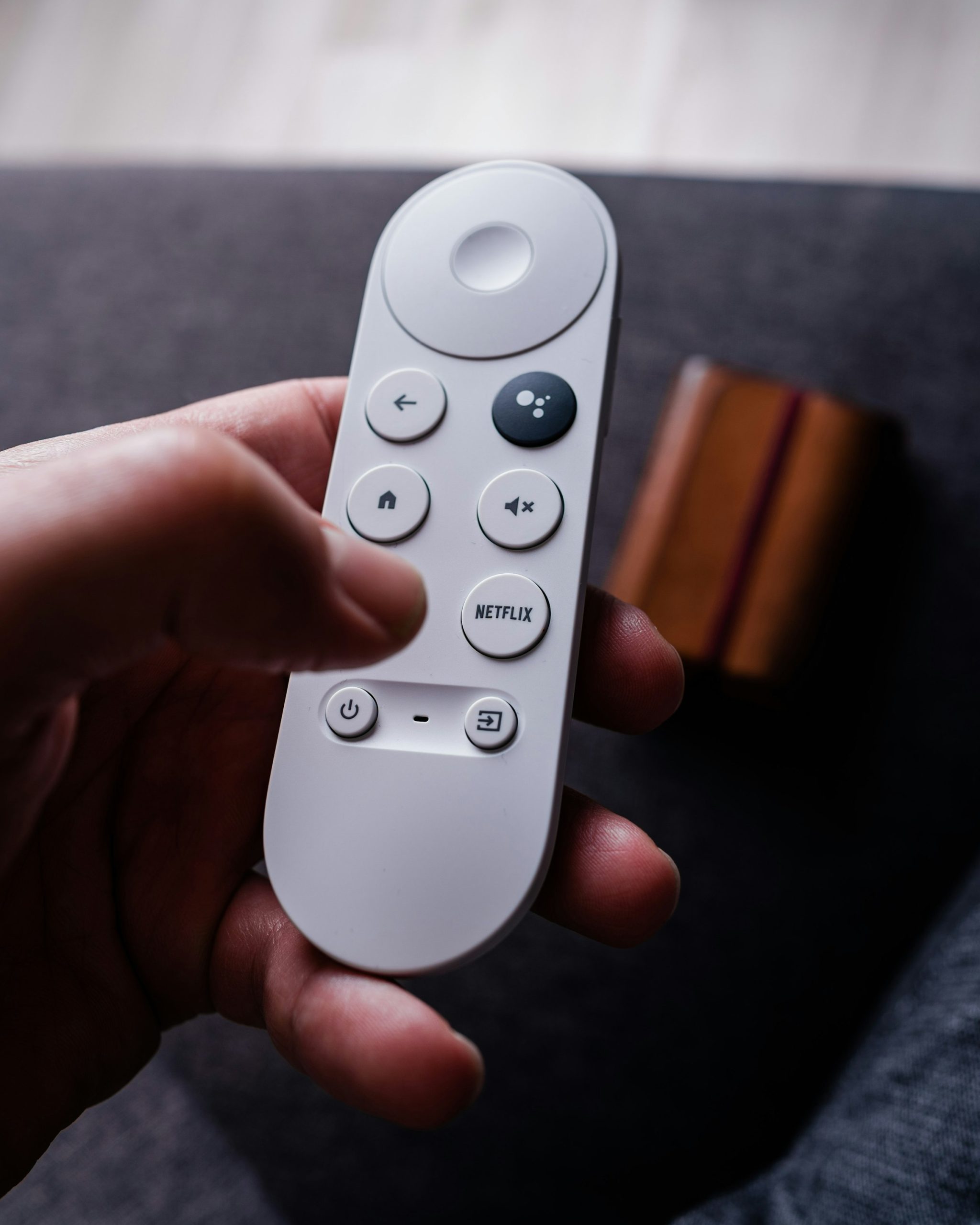 Main tenant une télécommande face à un téléviseur, illustration du choix entre plusieurs offres de streaming sportif