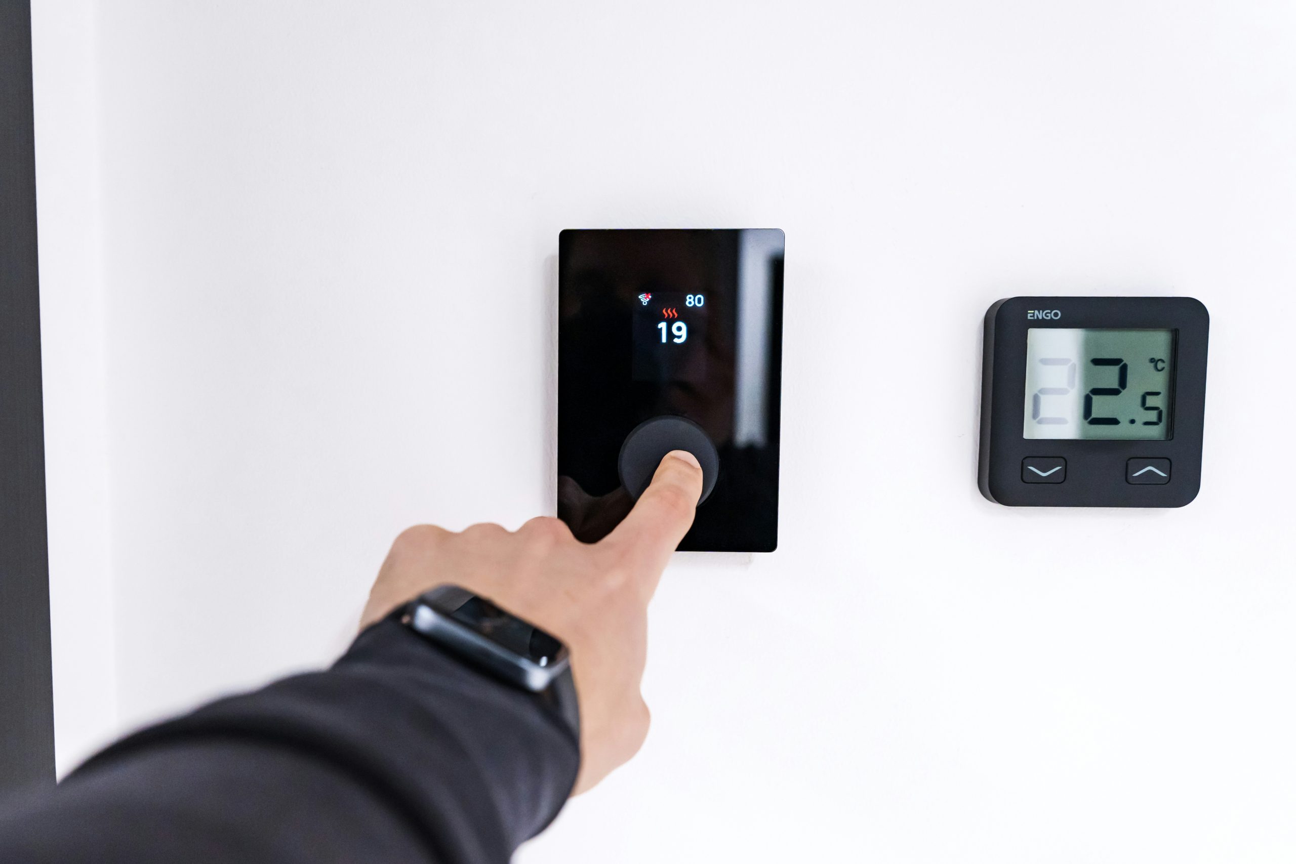 Doigt réglant la température sur un thermostat numérique mural